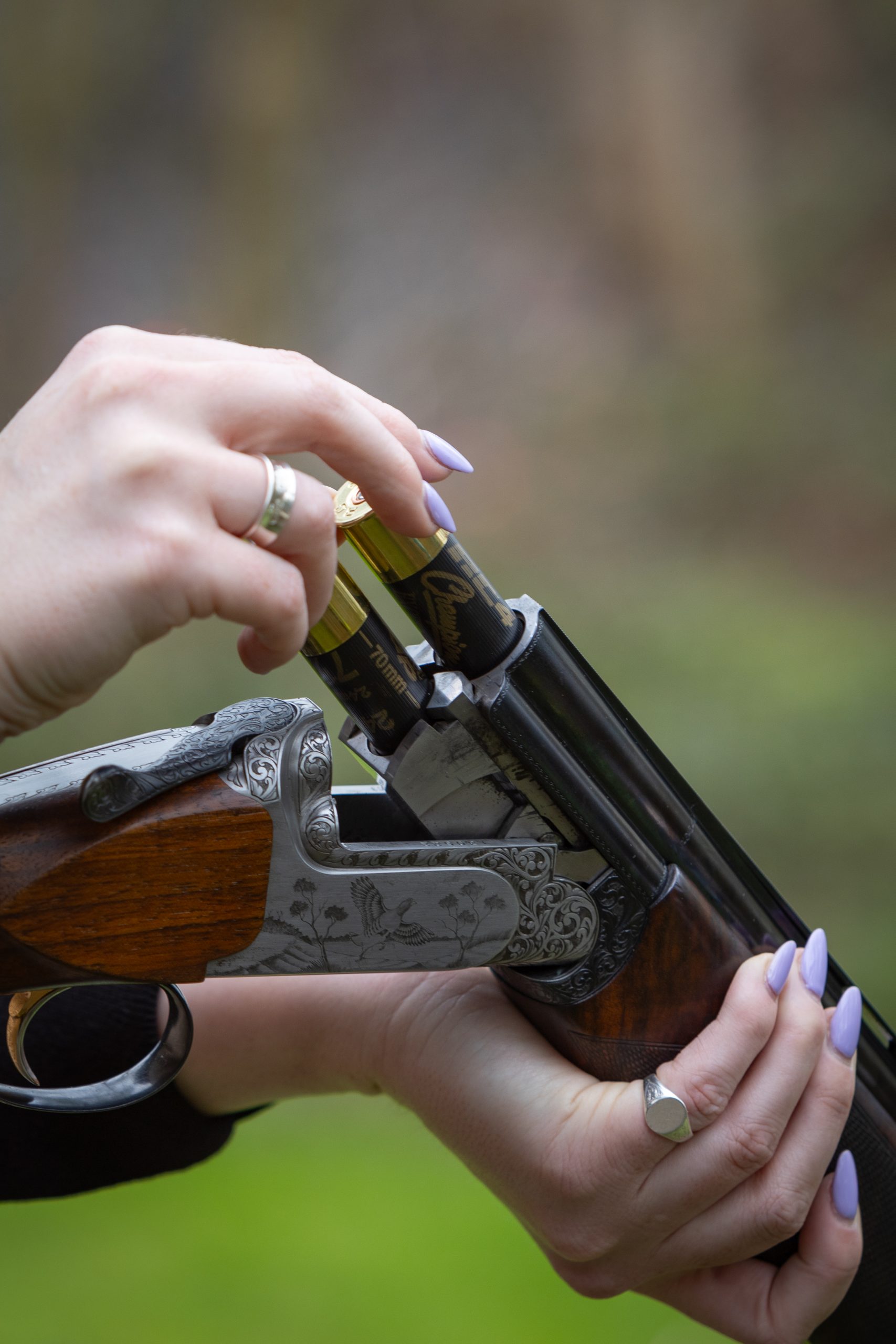 Woman loading to cartridges into an over and under shotgun