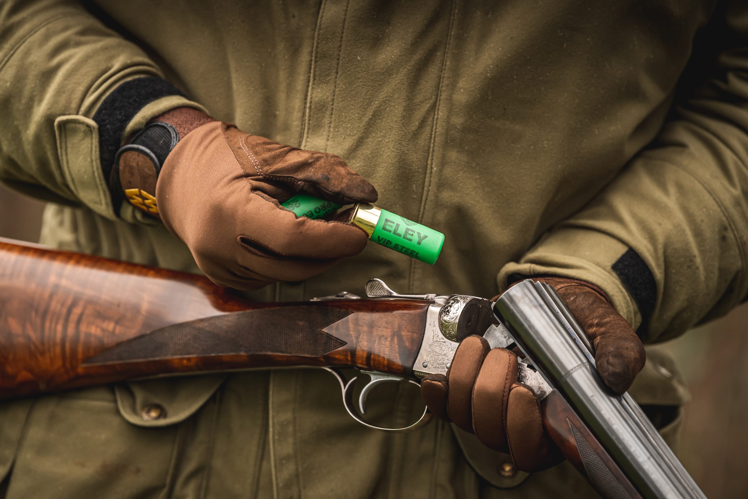 Man loading game cartridge into side by side shotgun